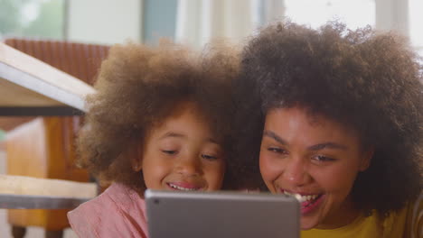 Mother-And-Daughter-Having-Fun-Lying-On-Floor-Streaming-Movie-On-Digital-Tablet-At-Home-Together