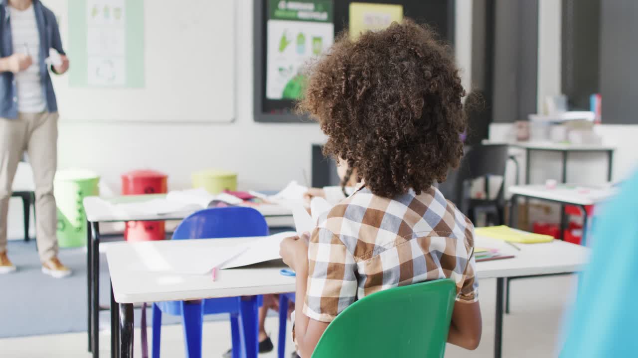 retrato de un niño de escuela afroamericano feliz en los escritorios dando la vuelta y sonriendo en el aula