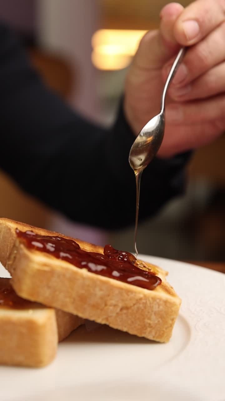 Hand Drizzling Honey on Toast with Jam