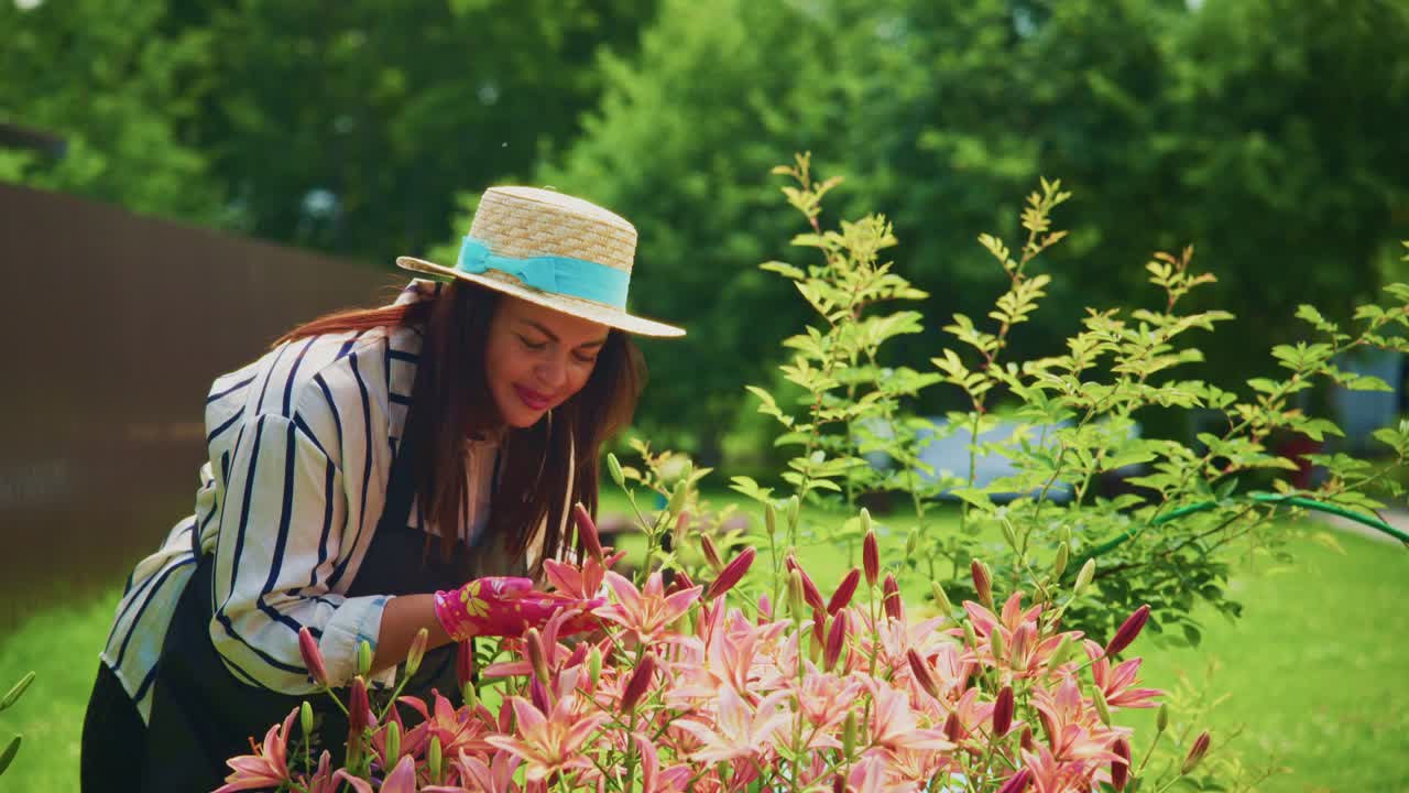 Woman in straw hat tending to vibrant flowers in a lush garden during sunny day