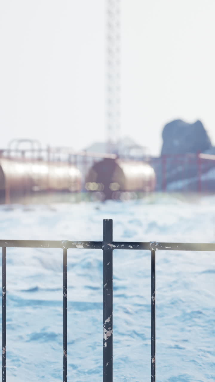 Ein Metallzaun vor einem verschneiten Industriegebiet