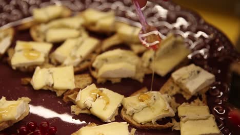 La-Miel-Se-Rocía-Sobre-Una-Bandeja-De-Queso-En-Pan-Para-Aperitivos-En-Una-Cena-Formal---Aislada