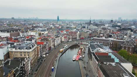 El-Dron-Vuela-Hacia-Adelante-Sobre-El-Canal-Rokin-Y-La-Calle-Con-Vistas-Al-Centro-De-La-Ciudad-En-Un-Día-Nublado-En-Amsterdam,-Países-Bajos,-Imágenes-Aéreas-4k