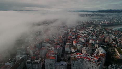 aerial view over clouds, misty cityscape of coruña city in spain with dense urban buildings