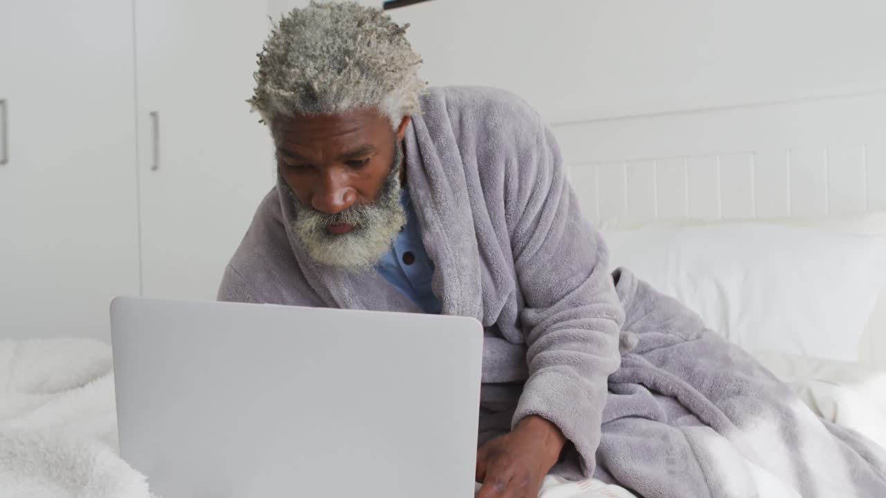 Senior man using laptop in bed at home