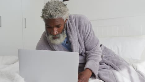 senior man using laptop in bed at home