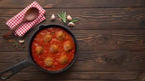 cooking meatballs with tomato sauce in black pan. flat lay, top view with copy space