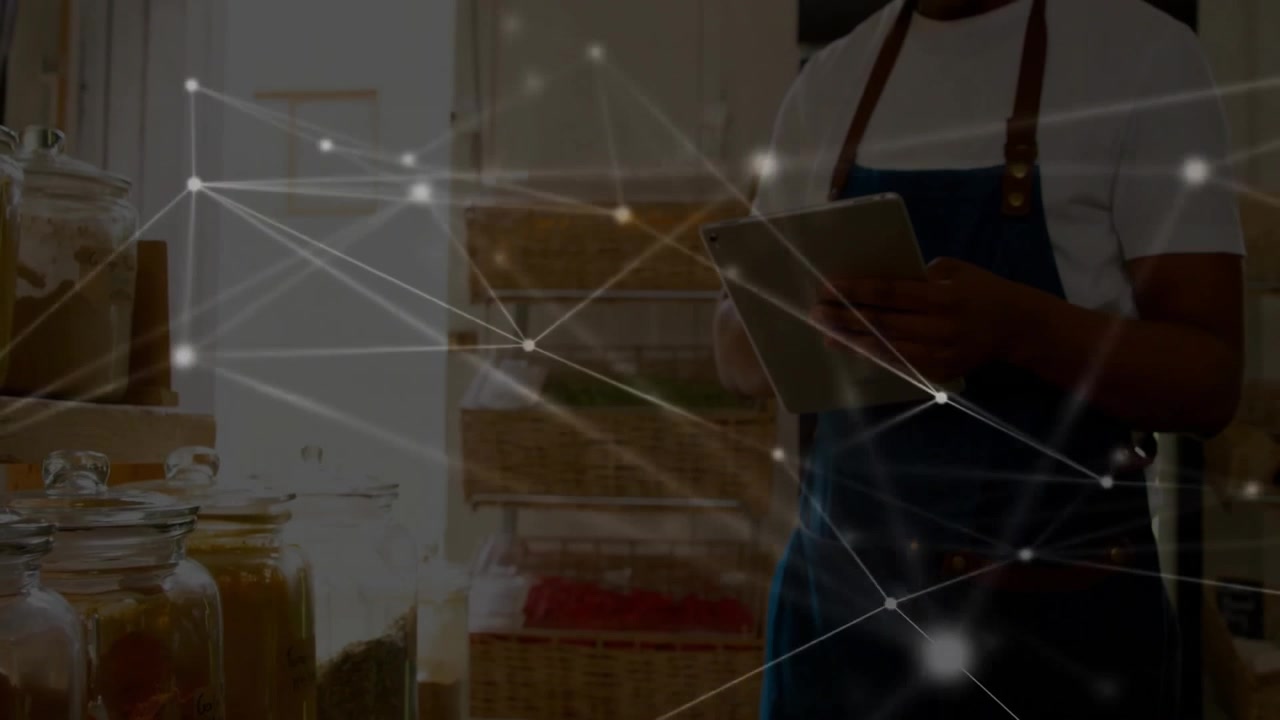With digital network overlay fading store clerk tapping tablet and inspecting jars for inventory