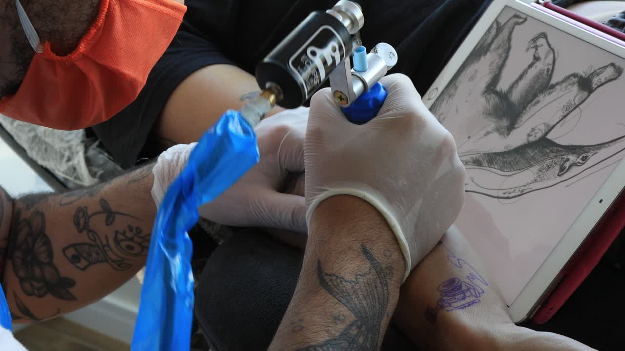 Tattoo artist making its draw on an arm