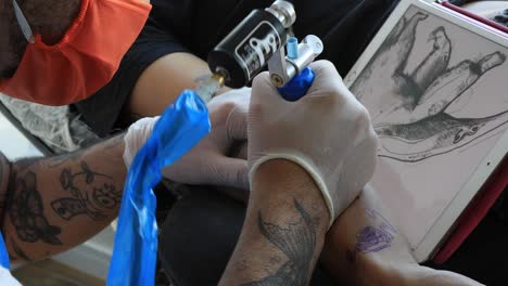 tatuador haciendo su dibujo en un brazo