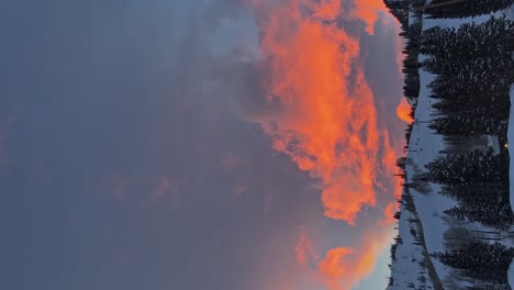 toma vertical de una impresionante puesta de sol de invierno con vivos colores naranja y rosa sobre una gran estación de esquí en las montañas rocosas de utah en una fría noche de invierno