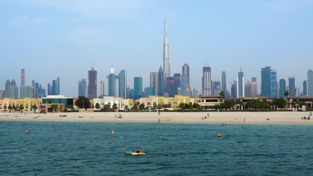 상징적인 두바이 스카이라인과 해변에서 여가를 즐기는 사람들의 꾸준한 철수 샷