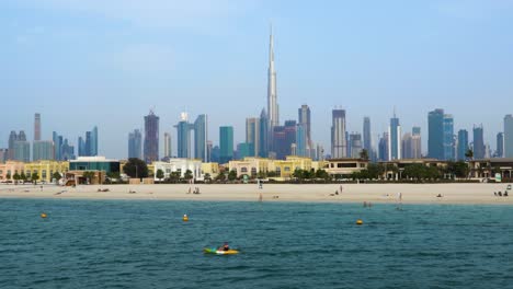 Toma-Continua-Del-Icónico-Horizonte-De-Dubai-Y-Gente-Disfrutando-De-Un-Día-De-Ocio-En-La-Playa