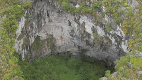 drone moving foward the sinkhole with a tiny person standing at the edge