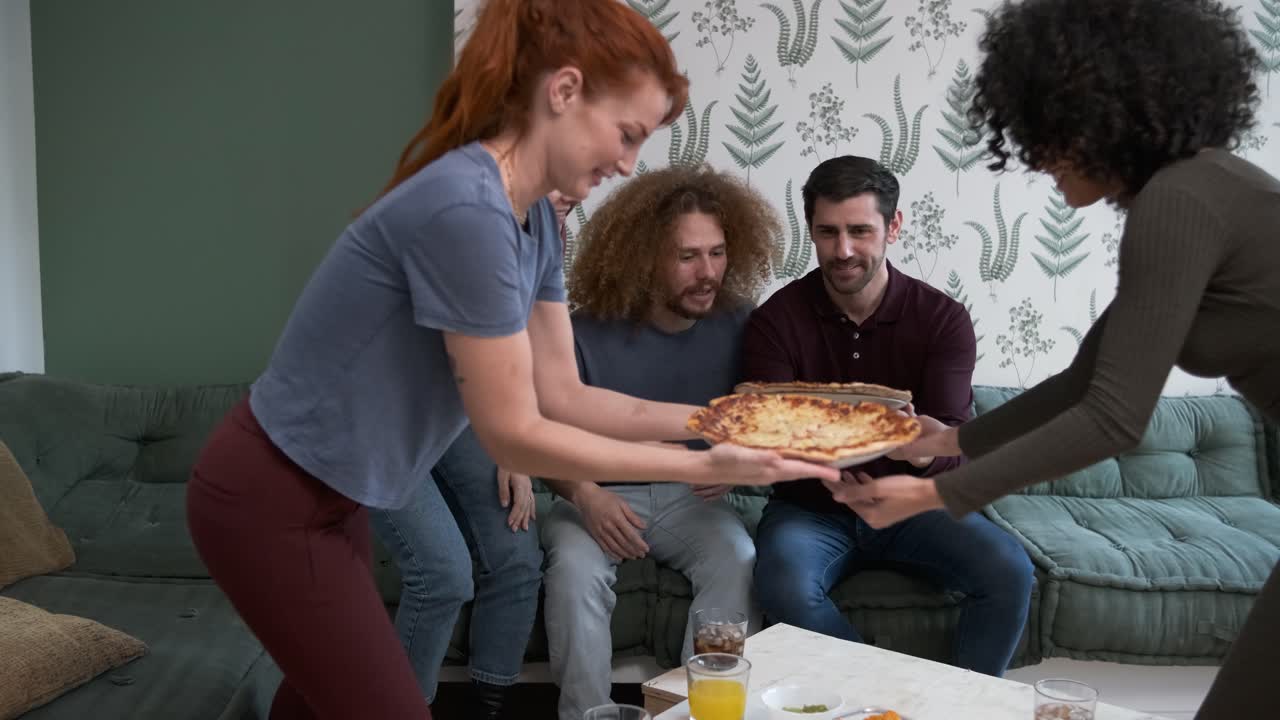 Diverse friends cheering up for woman bringing pizzas during weekend party at home