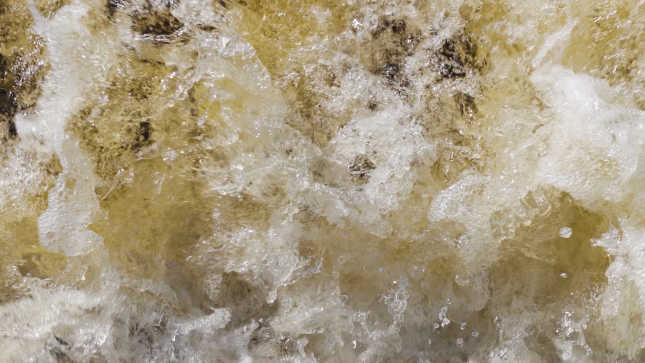 Close-up of the wildly splashing colored tannic water of a waterfall