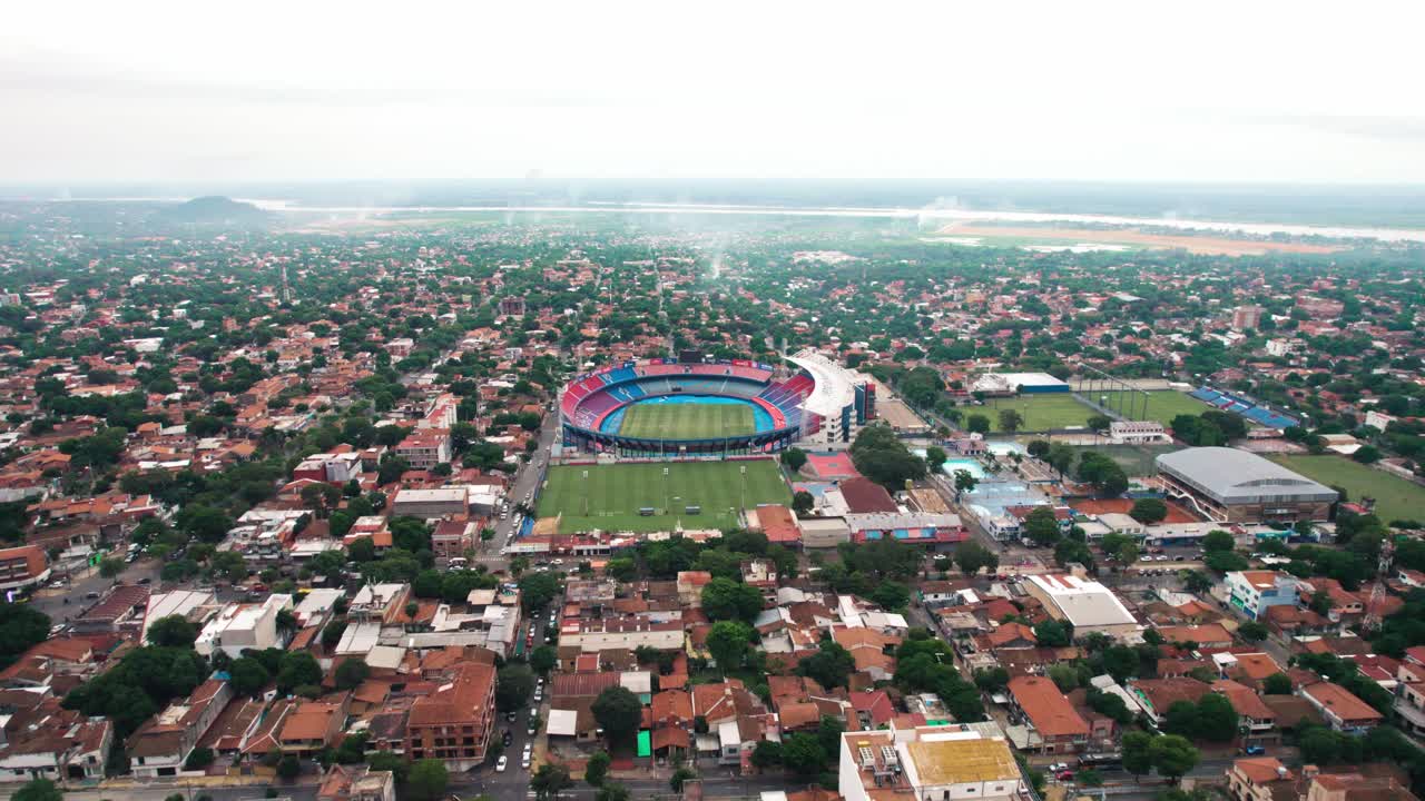 An aerial shot showcases the Estadio General Pablo Rojas stadium, locally known as La Nueva Olla, nestled within Asuncion, Paraguay. The surrounding urban landscape is dense