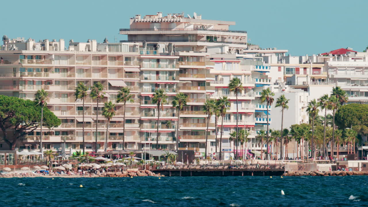Coastal view of modern apartments and tall palm trees along the waterfront in Cannes, France