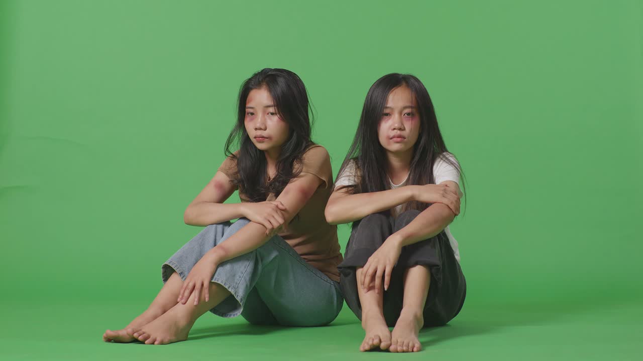 젊은 아시아 여성들의 몸은 폭력의 희생자입니다. 그들의 몸에 은 상처가 생겼습니다. 그것은 녹색 스크린 배경 스튜디오에서 신체적으로 학대당한 것으로 인해 발생했습니다.