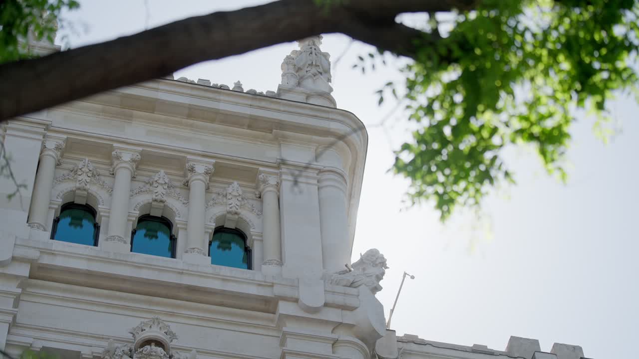 edificio español de cerca con llamarada solar a través de los árboles