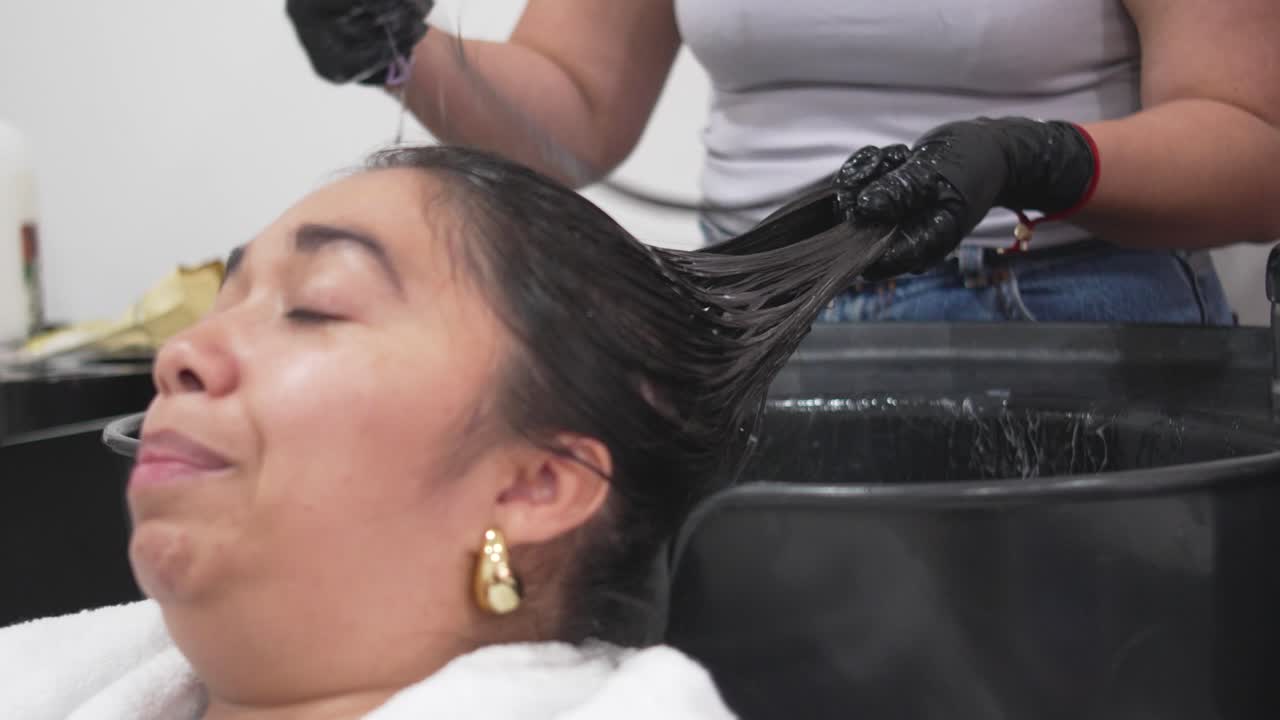 Latina woman undergoing restorative shampoo session for healthy, vibrant hair