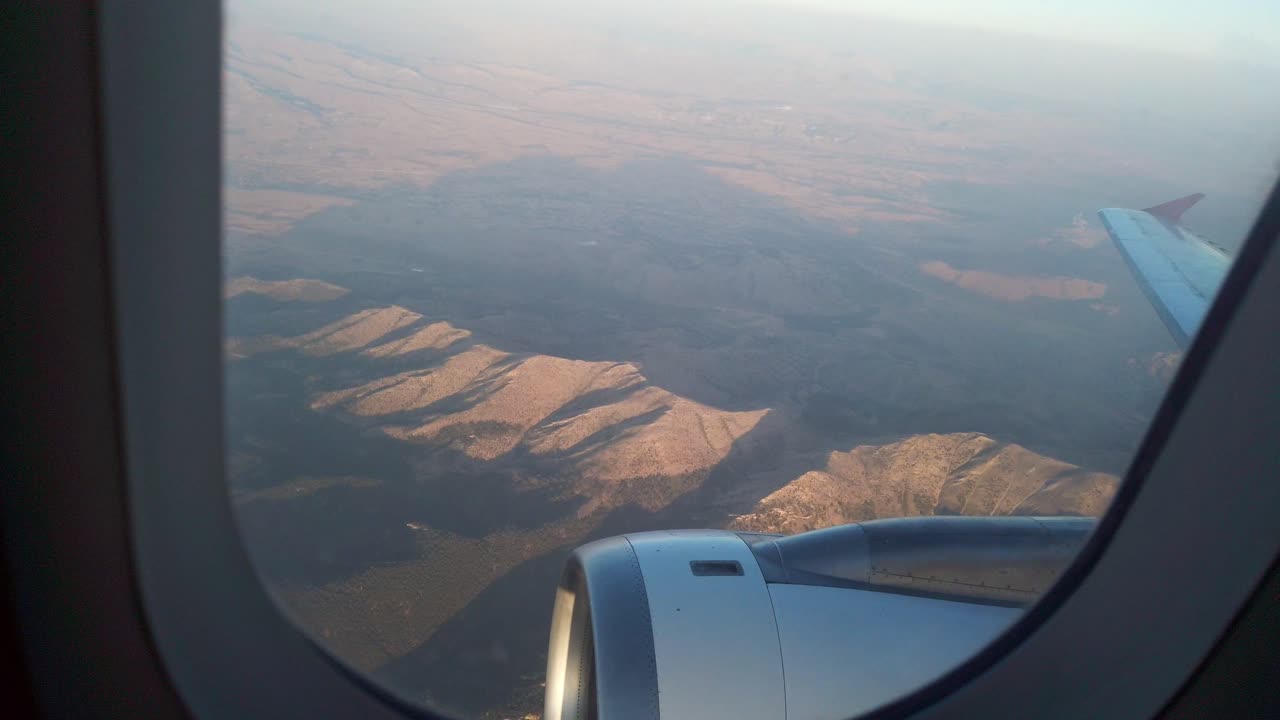 por la noche, una vista desde la ventana izquierda del avión captura una fotografía panorámica de las colinas en denizli, turquía, con largas sombras proyectadas detrás de las colina