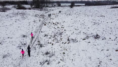 Drone-Tiro-Inclinado-Sobre-La-Gente-Caminando-En-Campo-Nevado-Campo-Reino-Unido