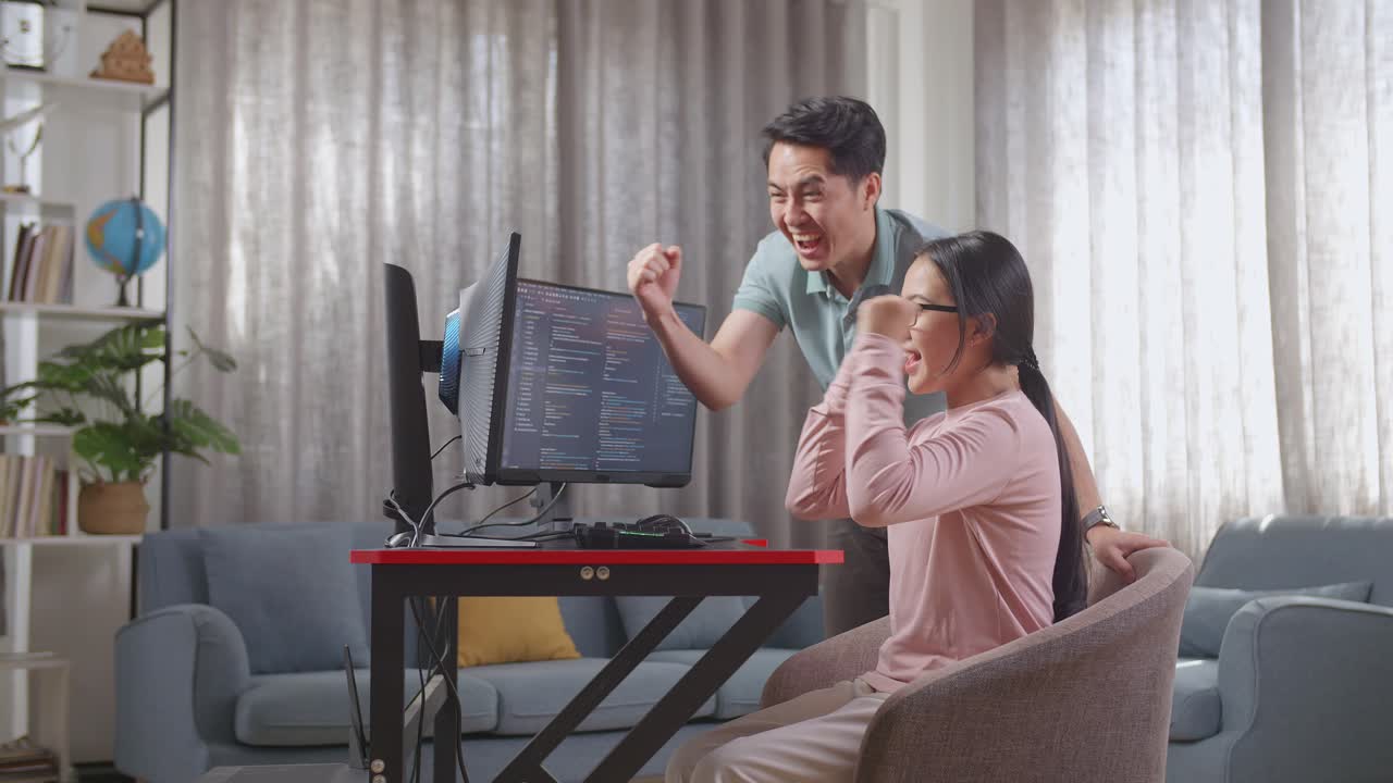행복한 커플이 집에서 코딩 성공을 축하하고 있습니다.