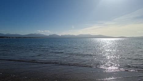 Dunstige-Snowdonia-Bergkette-über-Paradiesischer-Zeitlupe,-Schimmernde-Irische-Meereslandschaft-Von-Der-Küste-Von-Newborough-Aus