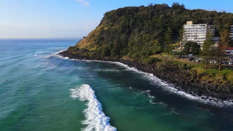 Turistas-Disfrutando-De-Las-Olas-Junto-A-Las-Montañas-Del-Parque-Nacional-Burleigh-Heads