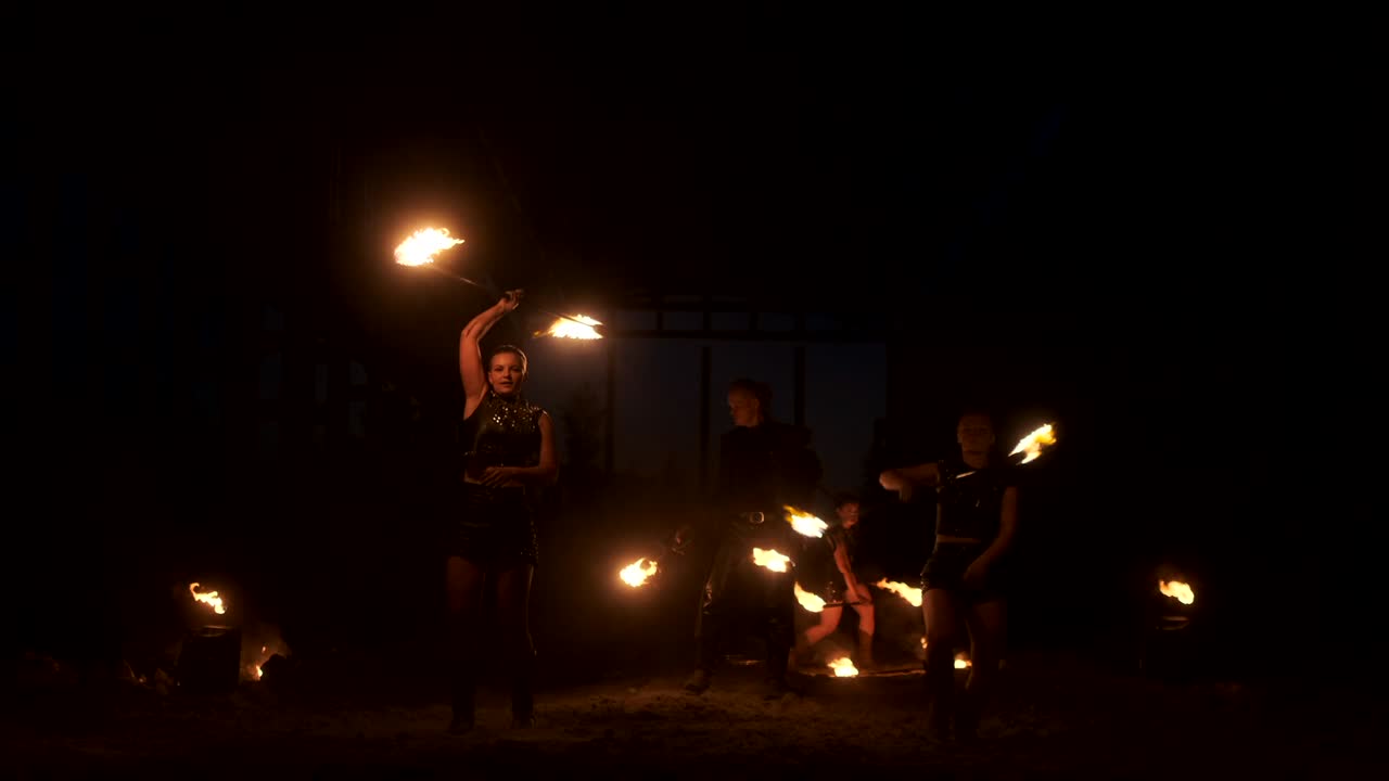 un grupo de artistas profesionales con fuego muestran el espectáculo haciendo malabarismos y bailando con fuego en cámara lenta.