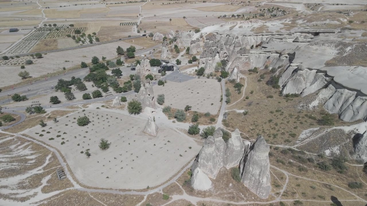 Türkiye, Kapadokya'da peri bacaları ve açık hava konser sahnesi mekanının üzerinden 4K 10-bit kuşbakışı drone çekimi. Eşsiz festival alanının güneşli bir yaz gününde çekilmiş havadan panoramik görüntüleri.