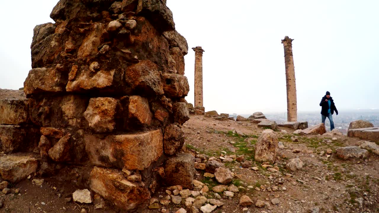 hombre camina en las ruinas del castillo de urfa dos columnas nieve y lluvia