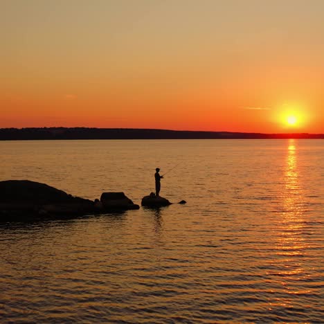 the fisherman fishes at sunset. a fisherman silhouette fishing at sunset. freshwater fishing, catch of fish. video from a side.