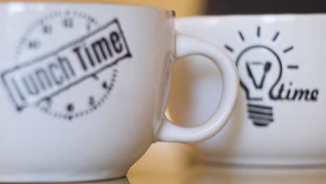 dos tazas blancas con diseños de hora de almuerzo