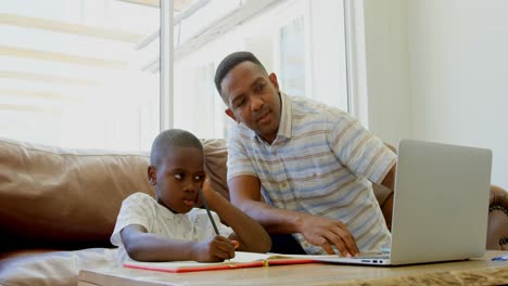 front view of young black father helping his son with homework in a comfortable home 4k