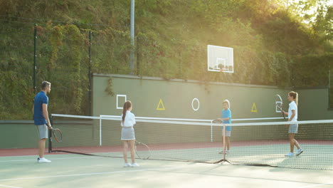 familia feliz jugando tenis en una cancha al aire libre en verano 5
