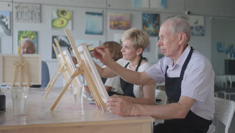 like senior friends attending together at a painting class. small group taking a variety of fun classes together. a group of elderly people attend a master class on drawing together spending time.