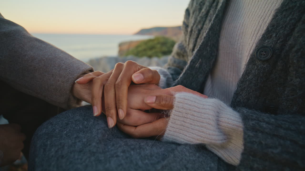 Romantic lovers connecting hands dating sunset sea closeup. Woman stroking man