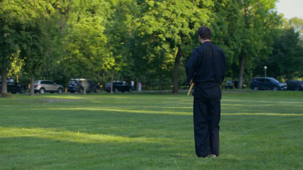 Uomo che pratica arti marziali con un bastone bo in un parco