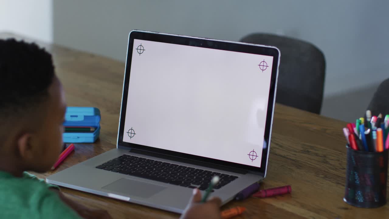 niño afroamericano haciendo una videollamada en una computadora portátil con espacio de copia mientras hace la tarea en casa