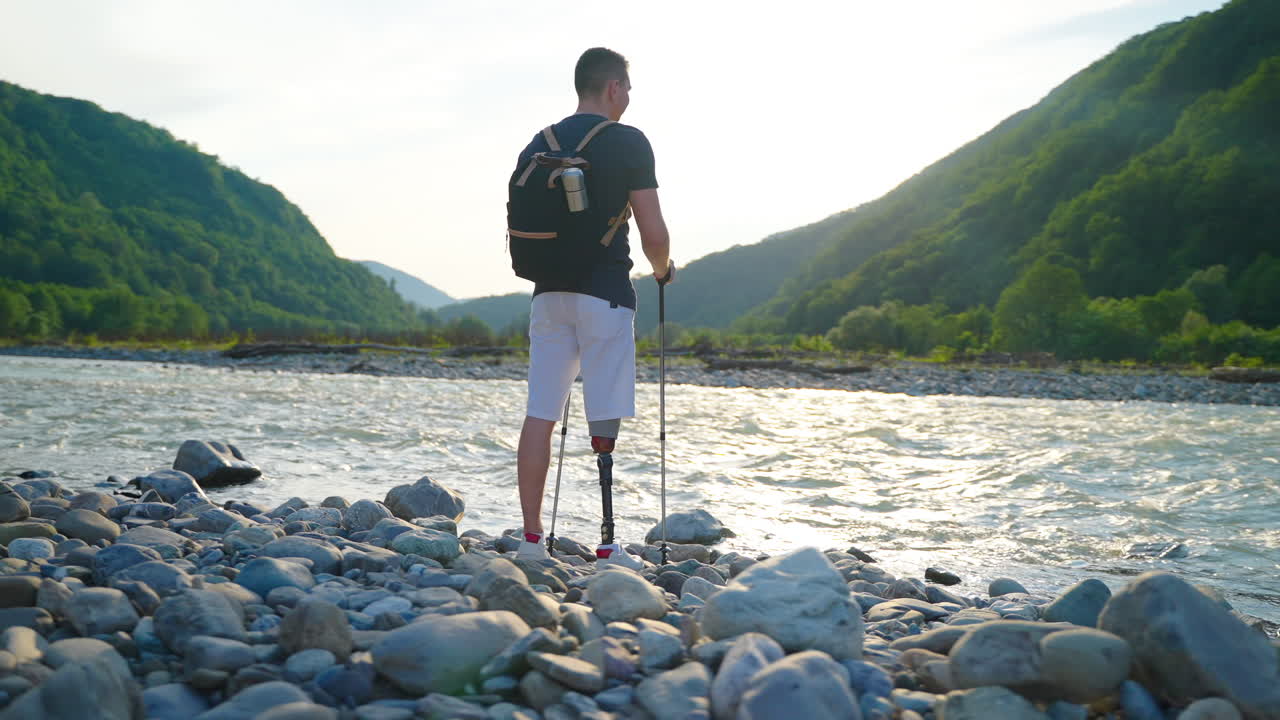 hombre con pierna protésica caminando por un río en las montañas