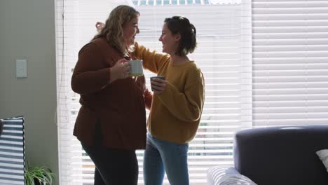 Caucasian-lesbian-couple-embracing-and-drinking-coffee