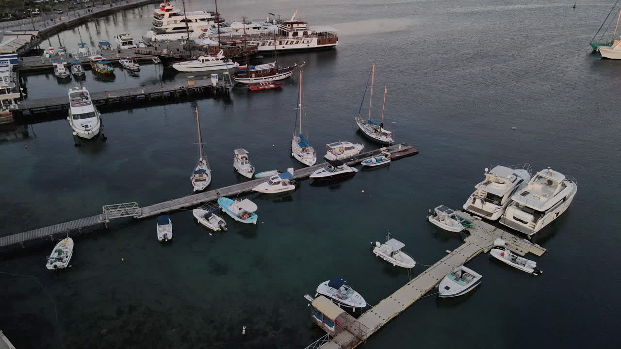 Ripresa aerea discendente di barche ormeggiate nel porto di Paphos al crepuscolo, Cipro.