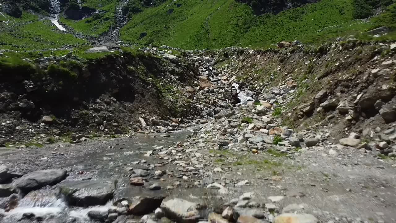 volando bajo hacia atrás sobre un arroyo de agua en austria con muchas rocas