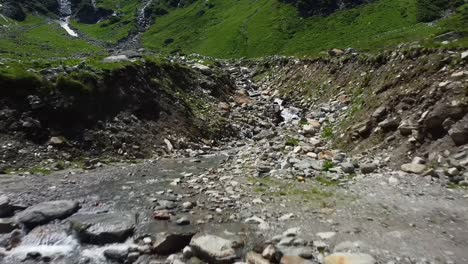 flying low backwards over a water stream in austria with lot of rocks