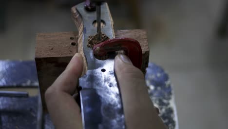 drill making a hole in a metal part of the knife in the middle of its production process