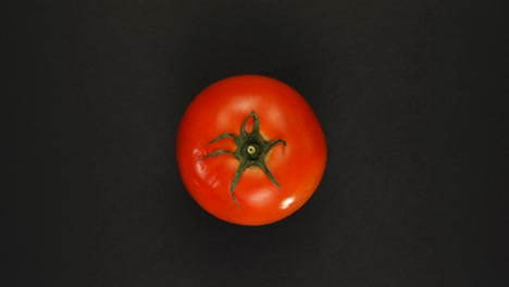 rotating whole tomato on a black background isolate. fresh juices, vegetable, vitamin and summer concept.