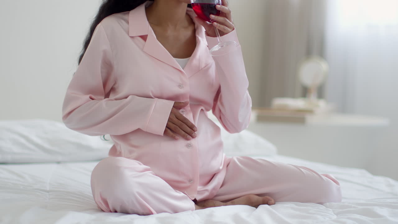 Pregnant woman in pajamas drinking wine/water