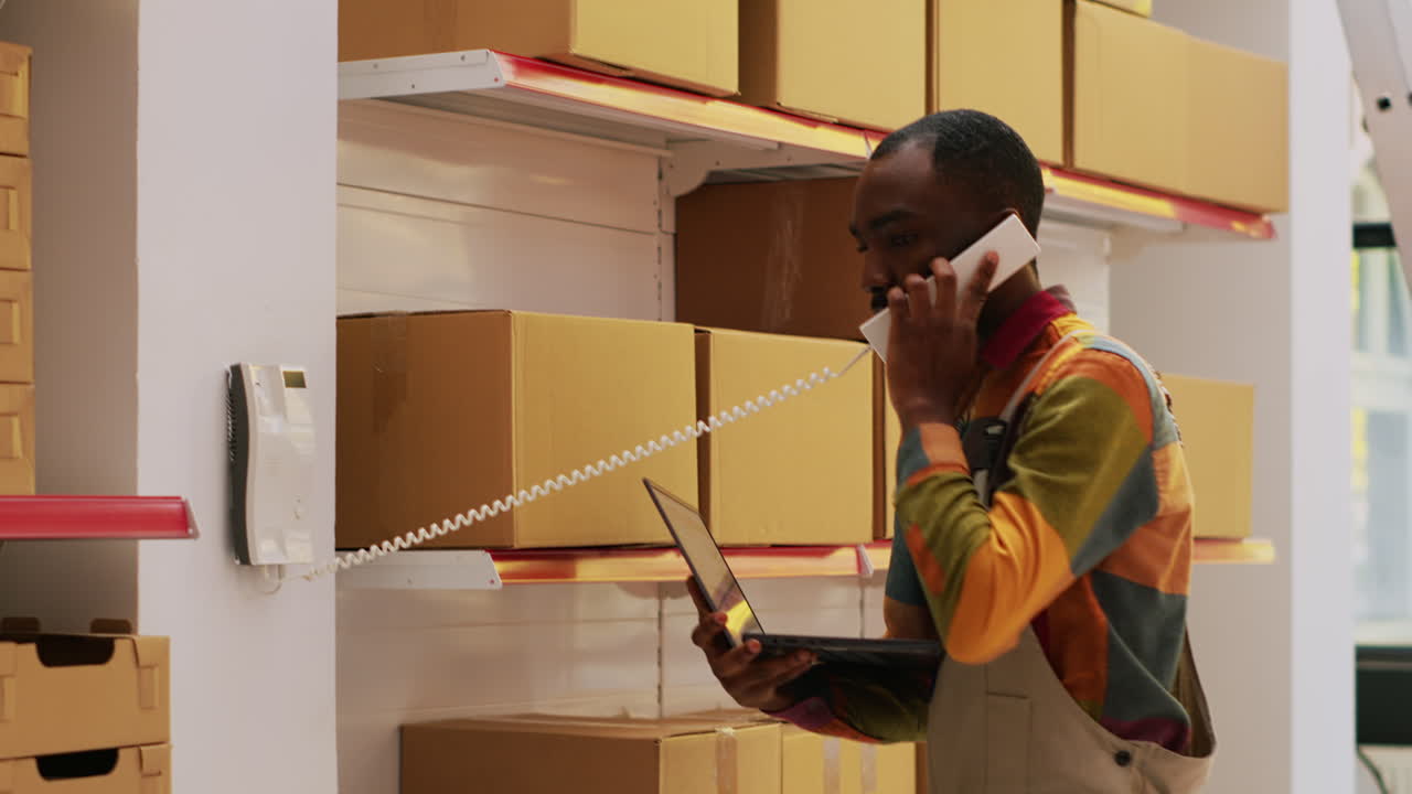 Warehouse worker checking inventory with phone and laptop